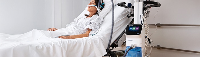 Dame ligger I en hospitalsseng tilsluttet til HAMILTON-HF90 system til high flow iltterapi